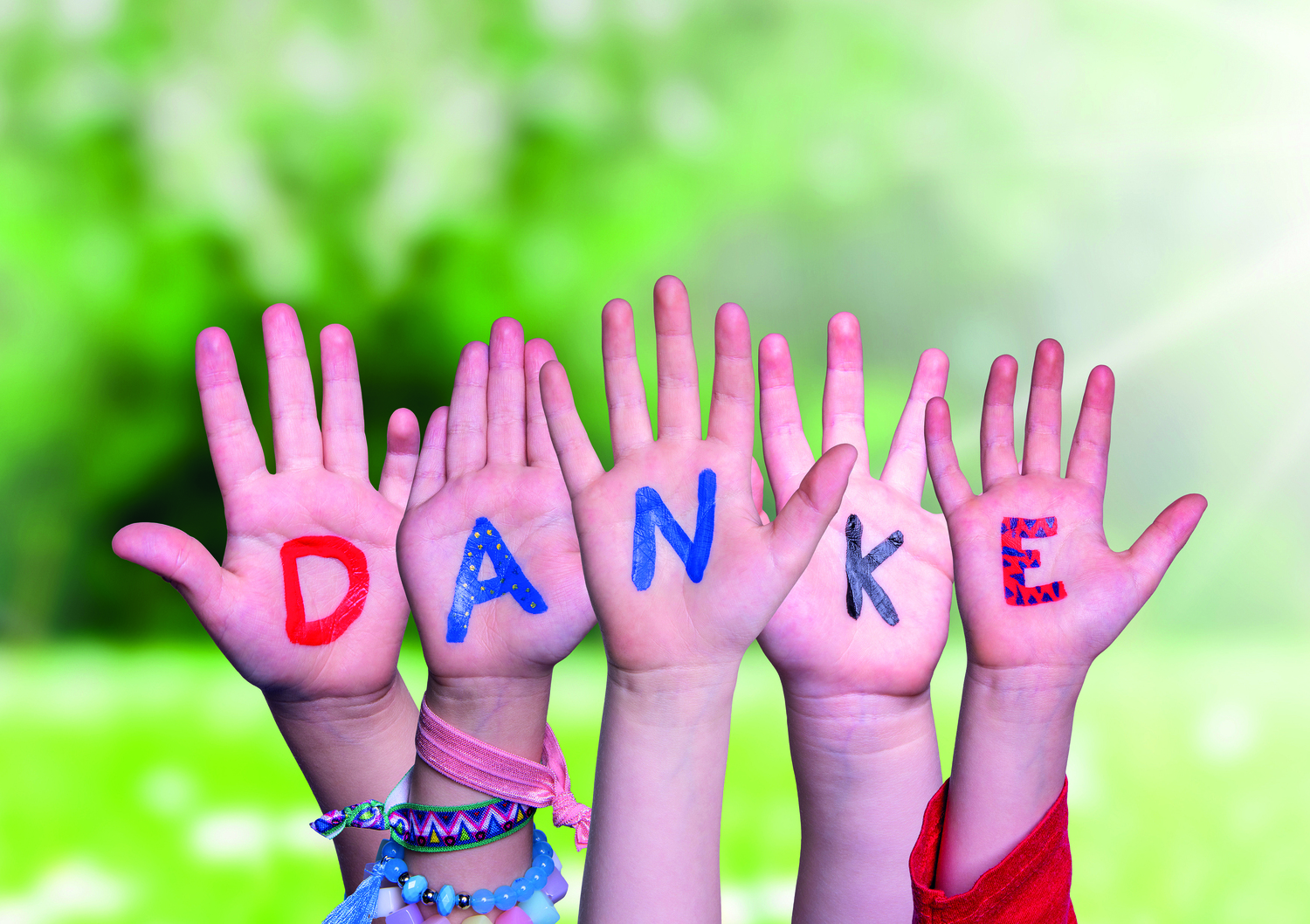 Kids Hands Holding Colorful German Word Danke Euch Allen Means Thank You All. Sunny Green Grass Meadow As Background